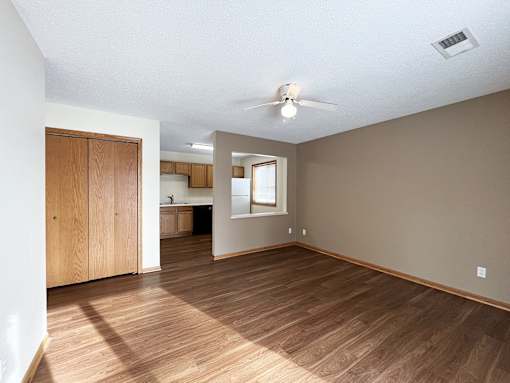 an empty living room with wood floors and a ceiling fan