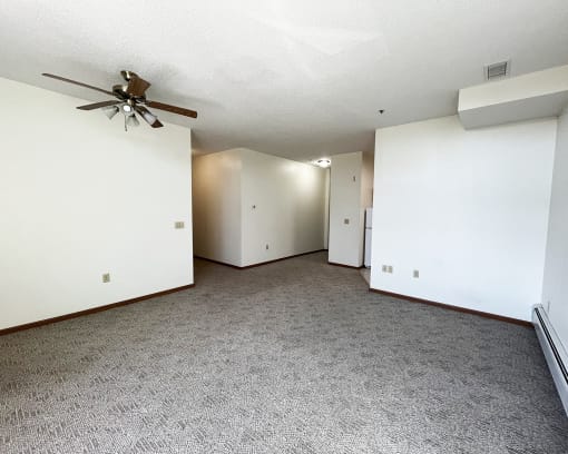 an empty living room with white walls and a ceiling fan