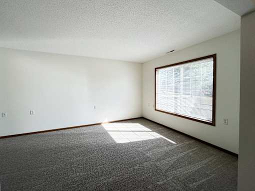an empty living room with a large window and carpet