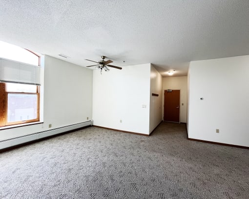 an empty living room with a ceiling fan and a window