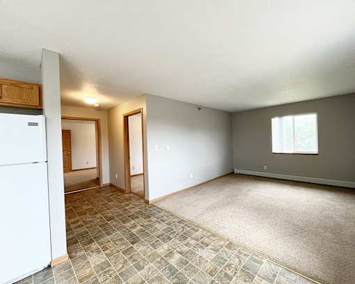 an empty kitchen and living room with a white refrigerator