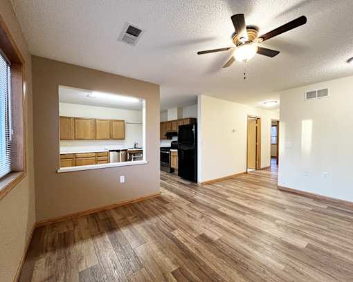 A room with a ceiling fan and wooden flooring.