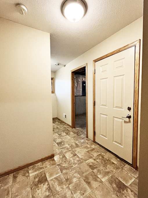 A hallway with a tiled floor and a white door.