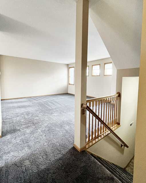 A room with a carpeted floor and a staircase.