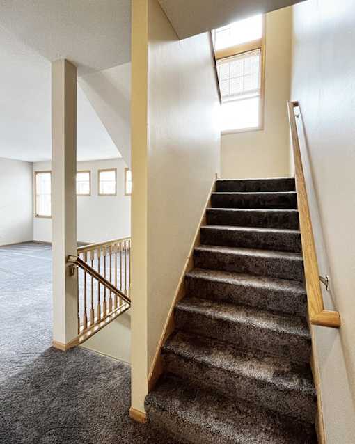 A staircase with a carpeted runner and wooden handrail.