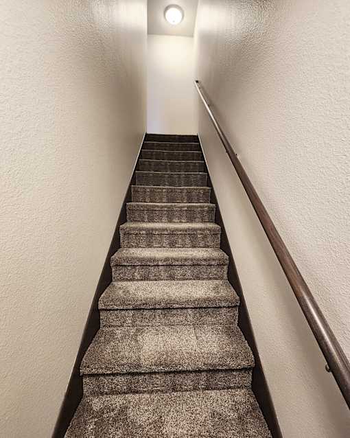 A staircase with a light on the wall.