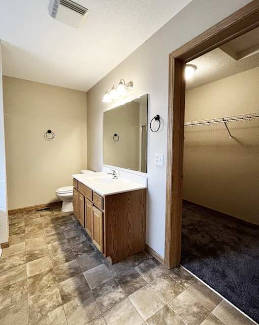 A bathroom with a toilet, sink, and mirror.