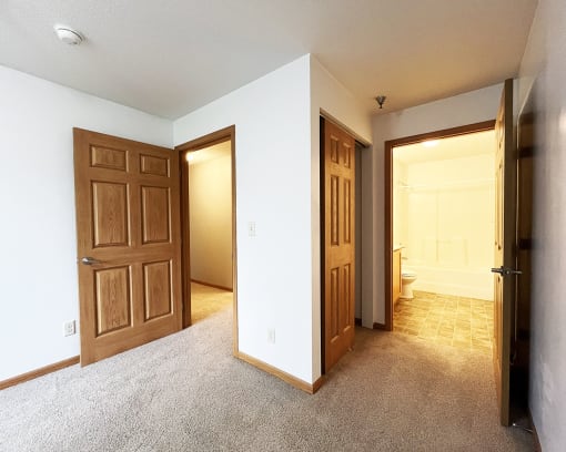an empty room with two doors and a bathroom