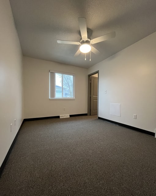an empty living room with a ceiling fan and a window