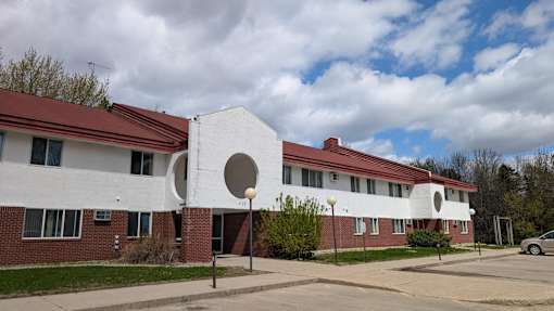 A white building with a red roof and a large circular window on the side.
