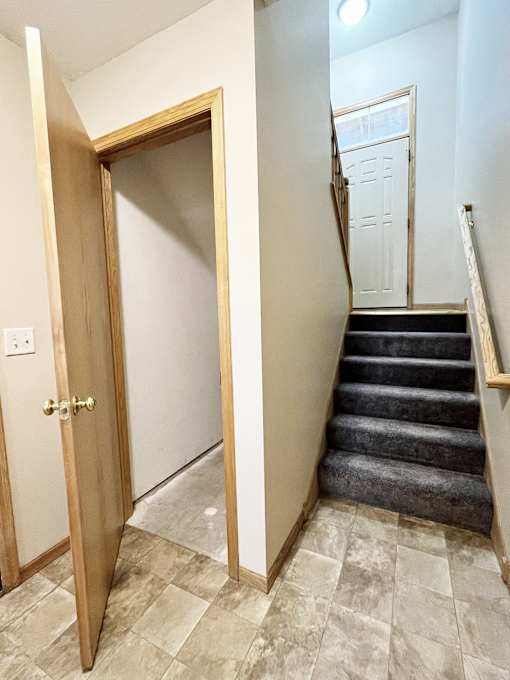 A wooden door is open to a hallway with a staircase.