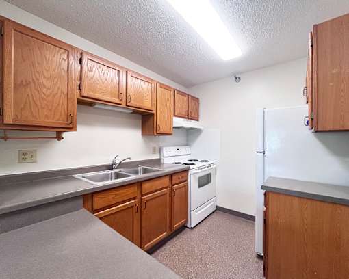 A kitchen with wooden cabinets and a white stove top oven.