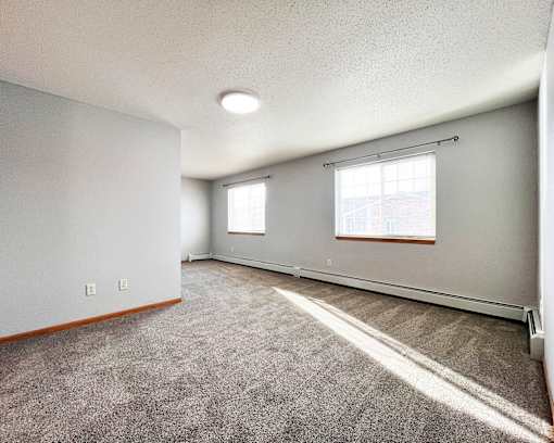 A room with a carpeted floor and a window with blinds.