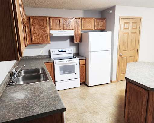 A kitchen with a white refrigerator, white oven, and white microwave.
