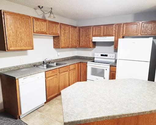 A kitchen with wooden cabinets and white appliances.