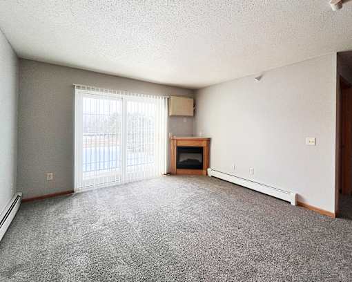 A sparsely furnished living room with a fireplace and sliding glass doors.