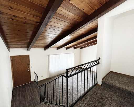 A room with a wooden ceiling and a black railing.