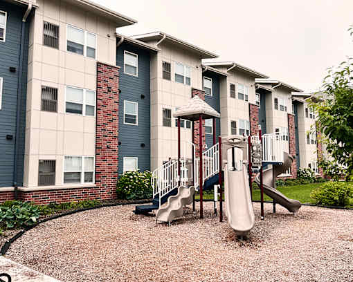 A playground with a slide in front of apartment buildings.
