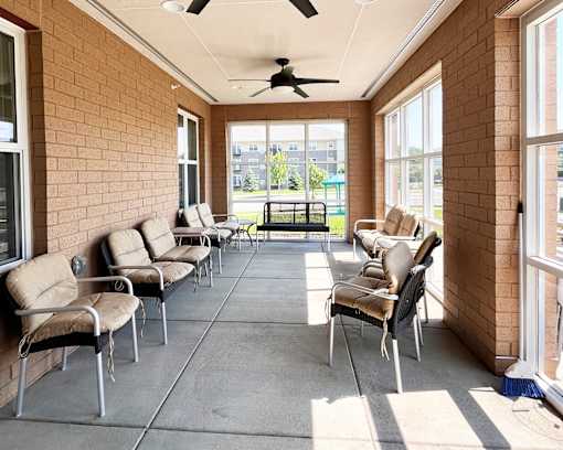 A patio with a row of chairs and a ceiling fan.