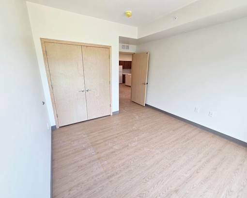 A room with a white wall and a wooden floor with two doors.
