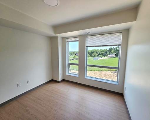 A room with a large window overlooking a green landscape.