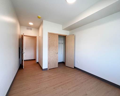 A room with wooden floors and white walls with two doors.