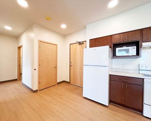 A kitchen with white appliances and wooden cabinets.