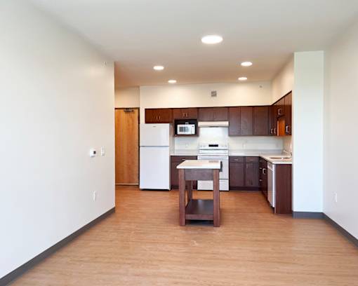 A kitchen with a white fridge and wooden floors.