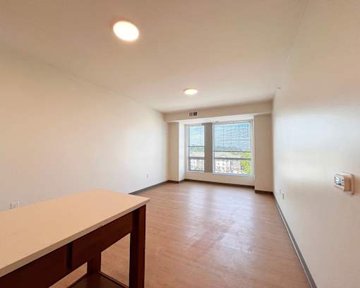 A room with a table and a window overlooking a green area.