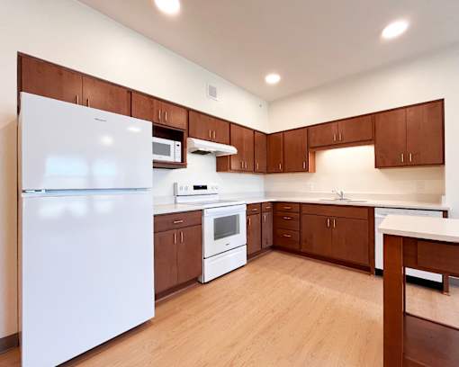 A kitchen with white appliances and brown cabinets.
