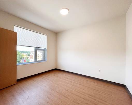 Empty room with a window and wooden floor.