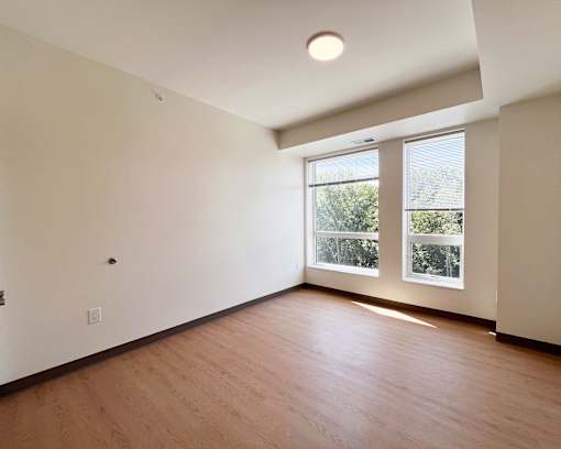 A room with wooden floors and a window overlooking a green area.