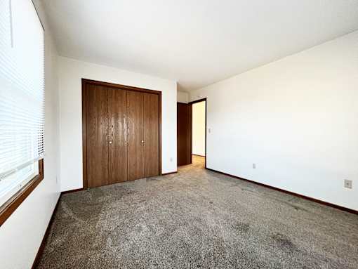 A room with a carpeted floor and two wooden doors.