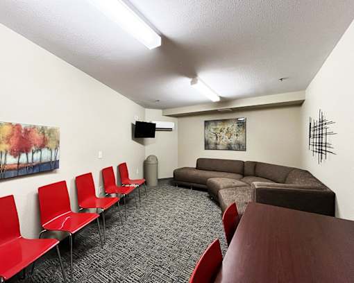 A room with a couch, chairs, and a television.