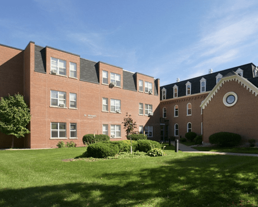 A large red brick building with a green lawn in front.