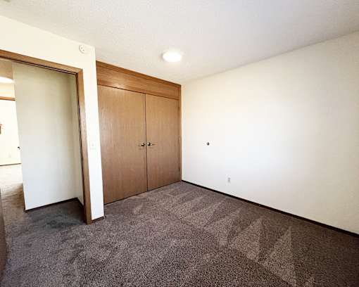 A room with a carpeted floor and a wall-mounted light fixture.