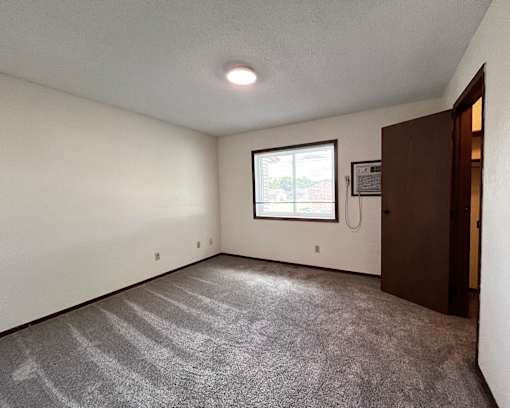 A room with a carpeted floor and a window.
