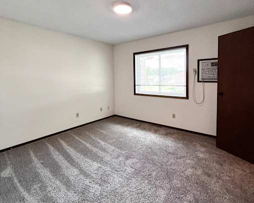 A room with a carpeted floor and a window.