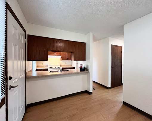 A kitchen with white walls and wooden cabinets.