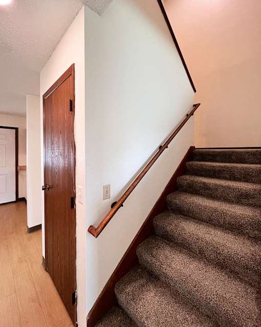 A brown door is on the left side of a staircase.