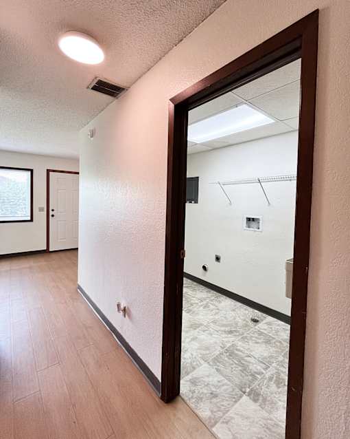 A hallway with a mirror on the wall and a door on the left.