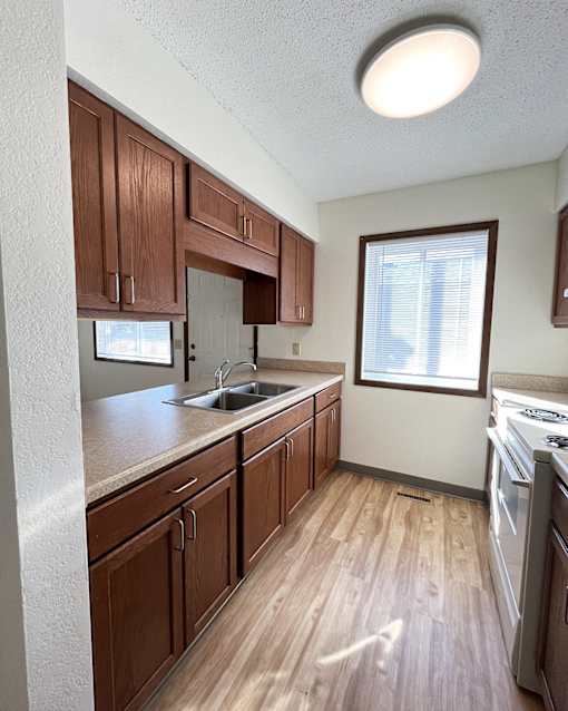 A kitchen with wooden cabinets and a white stove top oven.