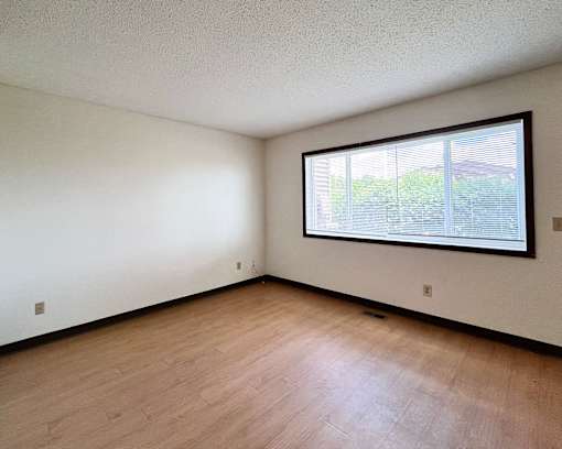 A room with a window and wooden flooring.