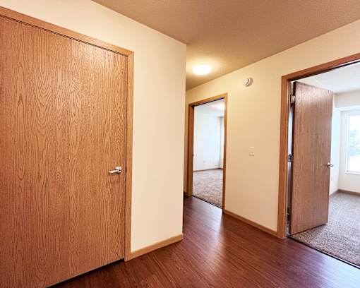 A hallway with a brown door on the left and a white door on the right.
