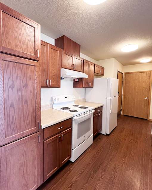 A kitchen with wooden cabinets and a white stove top oven.