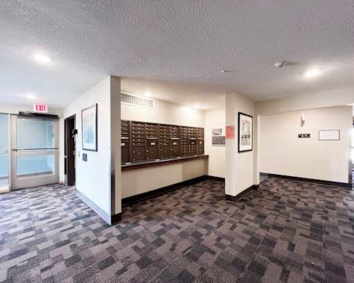 A hallway with a carpeted floor and a white wall with a framed picture on it.