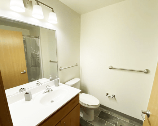 A bathroom with a toilet, sink, and mirror.