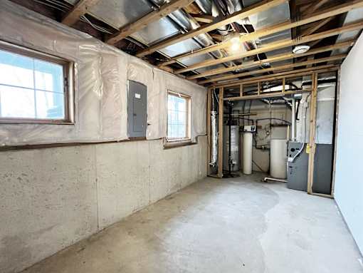 A room with a concrete floor and walls, with a window on the left and a door on the right.