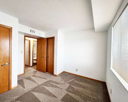 A room with a carpeted floor and two doors.