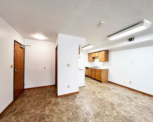A kitchen area with a refrigerator, cabinets, and a door.